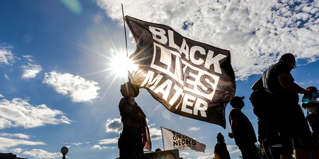 A woman holds a Black Lives Matter flag during an event in remembrance of George Floyd and to call for justice for those who lost loved ones to police violence outside the Minnesota State Capitol on May 24, 2021, in Saint Paul, Minnesota. 