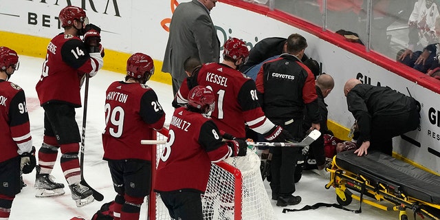 Arizona Coyotes watch as medical personnel and team officials attend to Clayton Keller, who crashed against the the boards during the third period of the team's NHL hockey game against the San Jose Sharks, Wednesday, March 30, 2022, in Glendale, Arizona.