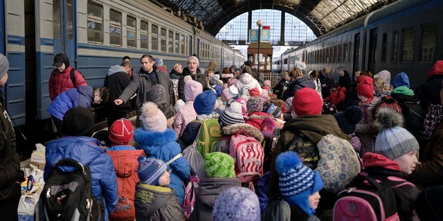 Children wearing backpacks gathered inside a train station in Ukraine. A small group of U.S. veterans are helping to taking orphans out of the country's east into safer parts of the west amid escalations by Russian forces.
