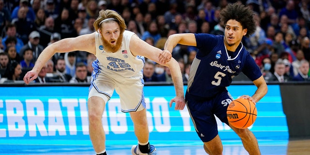 St. Peter's Daryl Banks III, right, tries to get past North Carolina's Brady Manek during the first half of a college basketball game in the Elite 8 round of the NCAA tournament, Sunday, March 27, 2022, in Philadelphia.