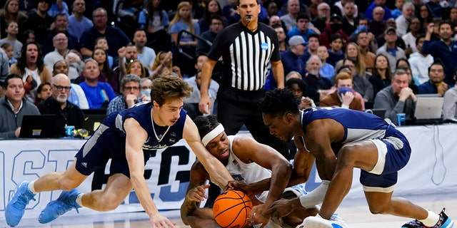 North Carolina's Armando Bacot, center, battles for a loose ball with St. Peter's Doug Edert, left, and KC Ndefo during the first half of a college basketball game in the Elite 8 round of the NCAA tournament, Sunday, March 27, 2022, in Philadelphia.