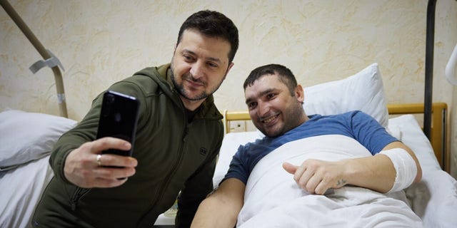 Ukrainian President Vladimir Zelenskiy takes a photo with a wounded soldier by Russian attacks on Ukraine during his hospital visit in Kyiv, Ukraine on March 13, 2022. 