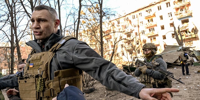 Kyiv Mayor Vitali Klitschko holds people away from a five-storey residential building that partially collapsed after a shelling in Kyiv on March 18, 2022.