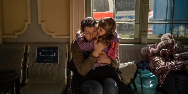 A Ukrainian evacuee hugs a child in the train station in Przemysl, near the Polish-Ukrainian border, on March 22, 2022, following Russia's military invasion launched on Ukraine. - The UN says almost 3,6 million people have fled Ukraine since the Russian invasion, with more than two million of them heading to neighboring Poland. 