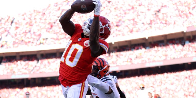 Wide receiver Tyreek Hill #10 of the Kansas City Chiefs catches a first quarter touchdown pass in front of cornerback Chidobe Awuzie #22 of the Cincinnati Bengals in the AFC Championship Game at Arrowhead Stadium on January 30, 2022 in Kansas City, Missouri. 