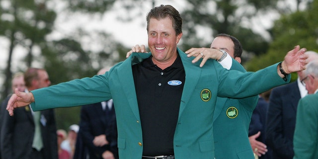 Phil Mickelson of the USA is presented the green jacket by 2003 Masters champion Mike Weir of Canada after the final round of the Masters at the Augusta National Golf Club on April 11, 2004, in Augusta, Georgia.