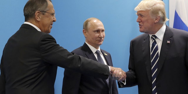 U.S. President Donald Trump (R) shakes hands with Russian Foreign Minister Sergei Lavrov as Russian President Vladimir Putin stands nearby. Sputnik/Mikhail Klimentyev/Kremlin via REUTERS