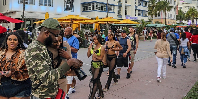 Despite the coronavirus, spring breakers return to South Beach and walk along Ocean Drive that is closed to traffic on Thursday, March 12, 2021. Miami Beach officials are imposing an emergency 8 p.m.-6 a.m. curfew effective immediately, saying large, out-of-control spring break crowds crammed the beaches, trashed some restaurant properties and brawled in the streets. Tourists and hotel guests are being told to stay indoors during the curfew hours. (Al Diaz/Miami Herald via AP)