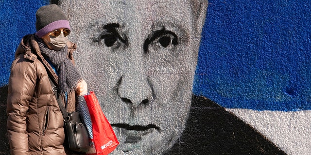 A woman passes by a mural depicting Russian President Vladimir Putin in Belgrade, Serbia, Saturday, March 12, 2022. 