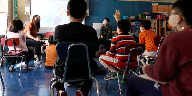 A teacher gives a lesson to masked students in their classroom at Yung Wing School P.S. 124 on Sept. 27, 2021, in New York City.