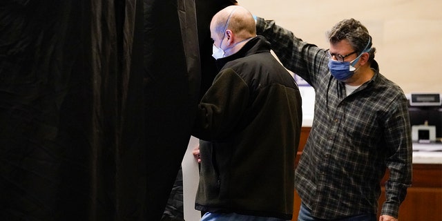 An election worker helps a voter into a booth at a polling place located at the Museum of the American Revolution in Philadelphia, Tuesday, Nov. 2, 2021.