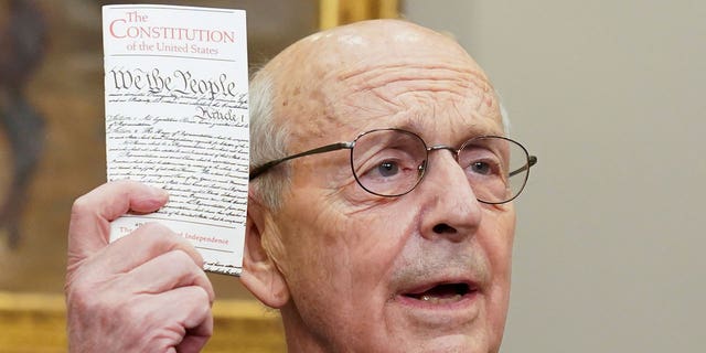 U.S. Supreme Court Justice Stephen Breyer holds up a copy of the U.S. Constitution as Breyer announces he will retire at the end of the court's current term, at the White House in Washington, U.S., January 27, 2022. REUTERS/Kevin Lamarque 