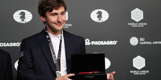 Sergey Karjakin of Russia wears a medal and holds a commemorative pen after losing to Magnus Carlsen of Norway at the 2016 World Chess Championship match in New York, Nov. 30, 2016. 