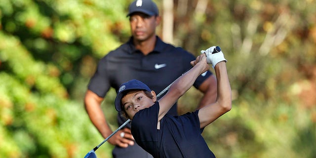 Charlie Woods tees off as his father, Tiger Woods, watches during the first round of the PNC Championship golf tournament on Dec. 17, 2021, in Orlando, Florida.