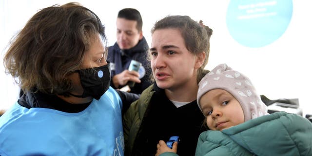 A Ukrainian mom, Karina, and her daughter Luna, age 3, speak with a UNICEF regional director for Europe and Central Asia inside Romania.