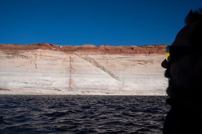 Guide Paul McNabb fishes for striped bass on Feb. 2, 2022, near Glen Canyon Dam near Page, Ariz. A high-water mark or bathtub ring is visible on the shoreline; Lake Powell was down over 168 vertical feet, at the time.