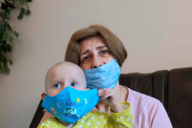 A Ukrainian grandmother holds her 22-month-old granddaughter, Yeva Vakulenko, at a clinic in Bocheniec, Poland, on March 17. She is among the more than 500 Ukrainian children with cancer who have been evacuated to Poland during Russia's invasion.