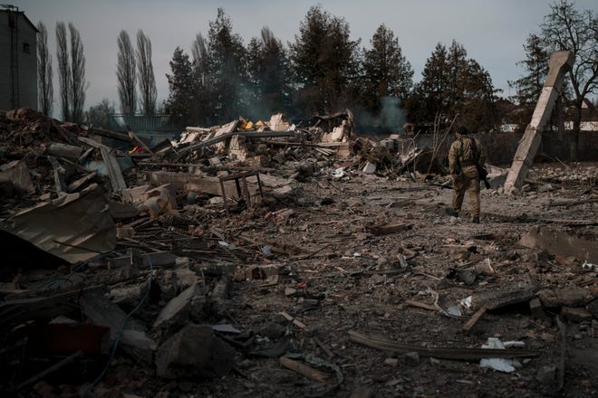 A volunteer of the Ukrainian Territorial Defense Forces walks on the debris of a car wash destroyed by a Russian bombing in Baryshivka, east of Kyiv, on Friday.