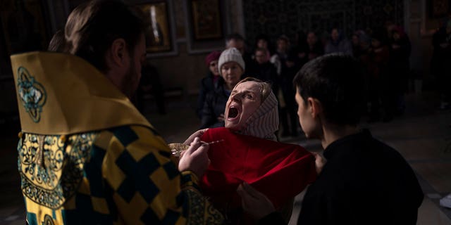 A woman receives communion inside the Transfiguration of Jesus Orthodox Cathedral, in Kyiv, Ukraine, Sunday, March 20, 2022.