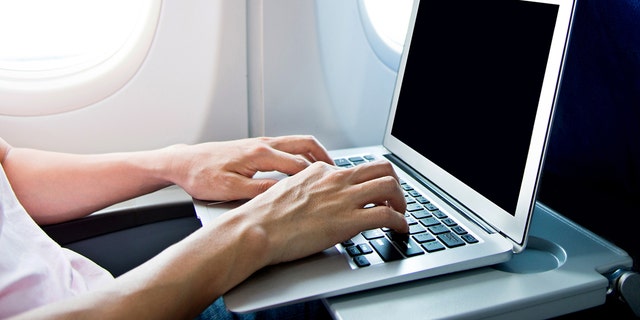 Man using laptop computer on airplane.