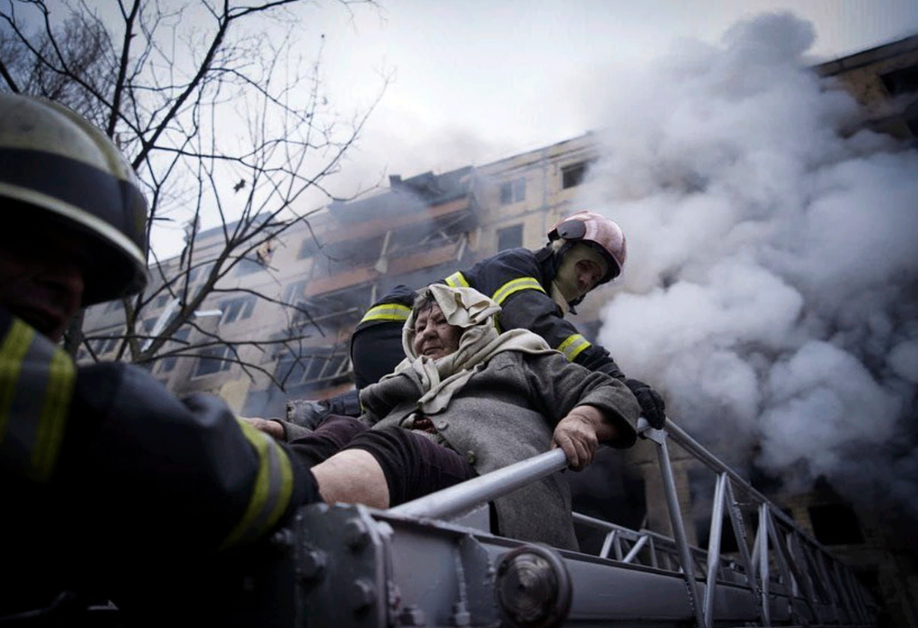 In this photo released by Ukrainian State Emergency Service press service, firefighters evacuate an elderly woman from an apartment building hit by shelling in Kyiv, Ukraine, Monday, March 14, 2022. 
