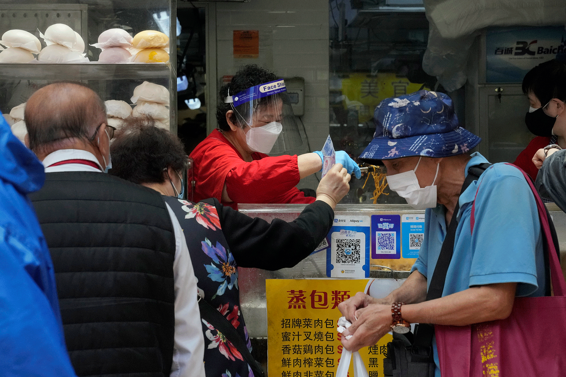 People wearing face masks line up to buy lunch boxes for take-away orders at a shop in Hong Kong, Sunday, March 13, 2022. The territory's leader, Chief Executive Carrie Lam, warned the peak of the latest surge in coronavirus infections might not have passed yet. 