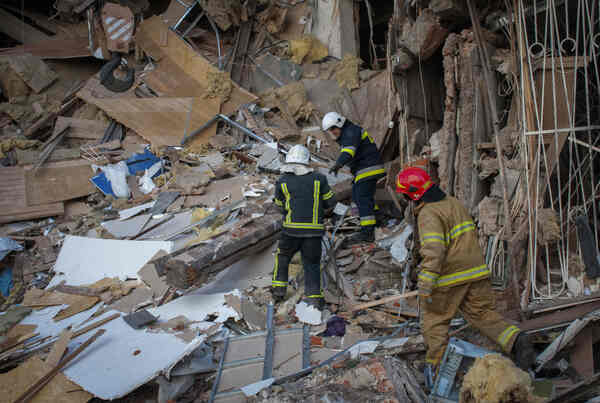 Workers in hardhats pick through wreckage.