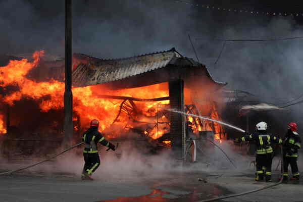 Firefighters spray water on a burning building.