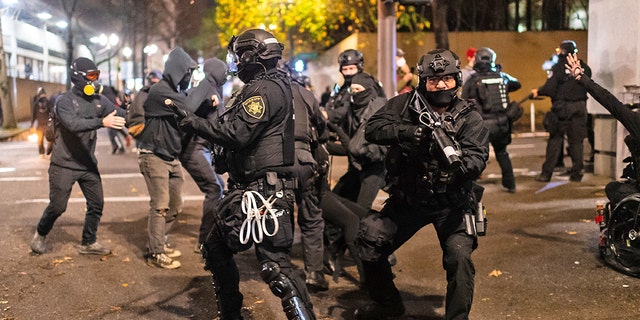 Police rush protesters at the south entrance of the Justice Center during a protest to decry the verdict in the Kyle Rittenhouse Trial. Portland, Oregon, USA, November 19th, 2021.