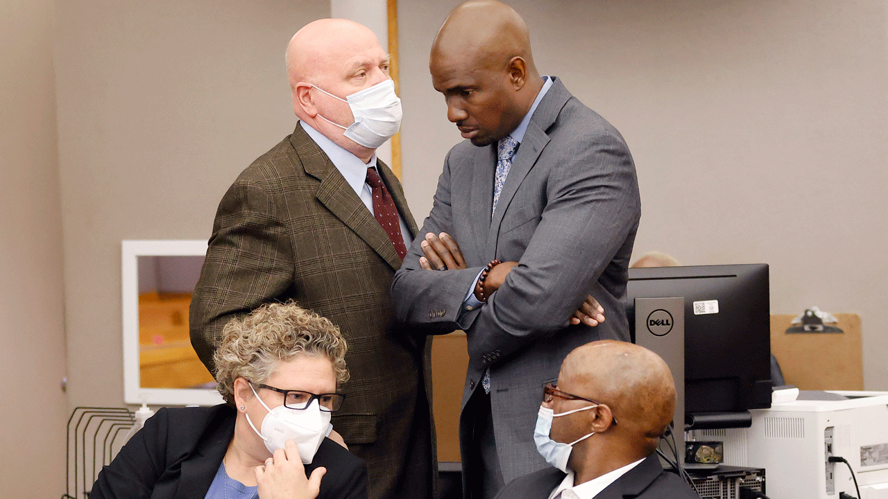 Defense attorney Kobby Warren, standing, right, listens to attorney Mark Watson, top left, as his client Billy Chemirmir, seated right, waits for motions and language being sent to the jury in his capital murder trial at the Frank Crowley Courts Building in Dallas, Friday, Nov. 19, 2021. He was joined by private investigator Tonia Silva seated, left. 