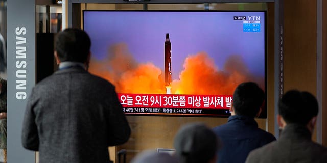 People watch a TV screen showing a news program reporting about North Korea's missile with file footage, at a train station in Seoul, South Korea, Wednesday, March 16, 2022. 