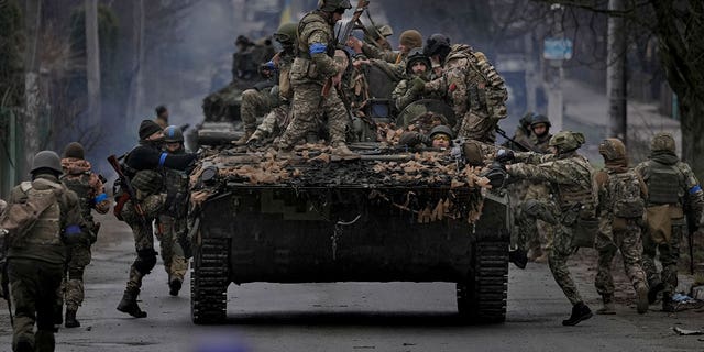Ukrainian servicemen climb on a fighting vehicle outside Kyiv, Ukraine, Saturday, April 2, 2022. 
