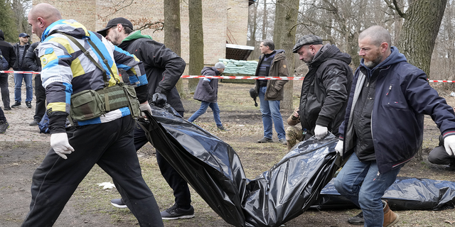 Volunteers carry the bodies of murdered civilians in Bucha on Monday.