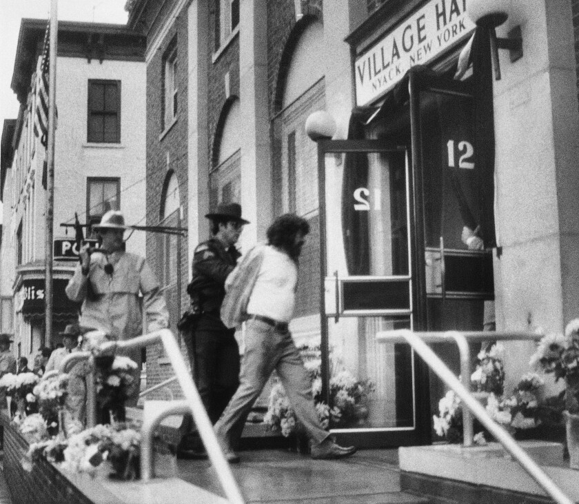 Officers walk a man into a building.