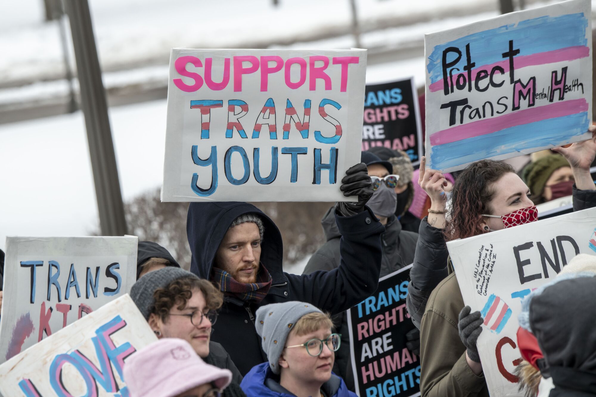 People hold signs at a rally.