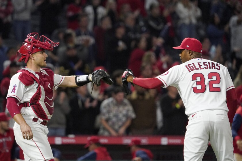 Angels catcher Max Stassi and relief pitcher Raisel Iglesias congratulate each other.