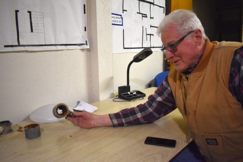 Photo depicting Steve Barton in a tan work vest holding a pipe on a workbench.