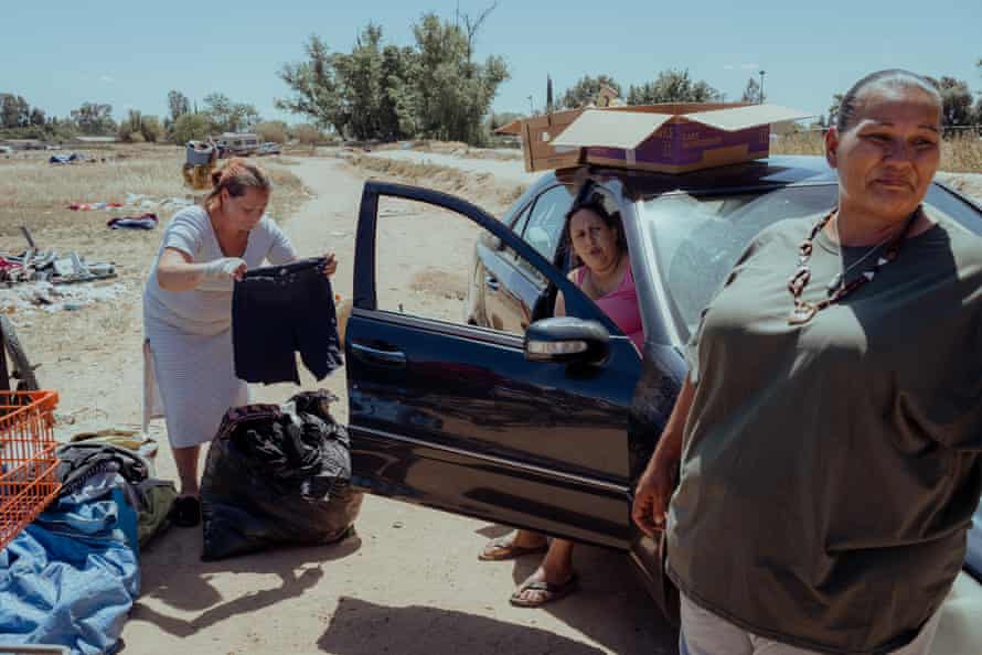 Three women by a car, one woman holding shorts