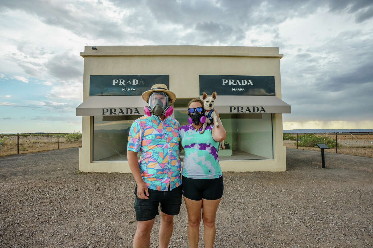  Josh Brasted (L) and Mary Alice Sandberg pose for a photo in respirators in front of the Prada Marfa sculpture by artists Elmgreen and Dragset. (Photo by Josh Brasted/Getty Images)