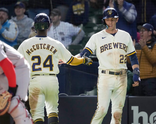 Brewers outfielder Christian Yelich congratulates Andrew McCutchen after scoring on a Tyrone Taylor double during the seventh inning Sunday.