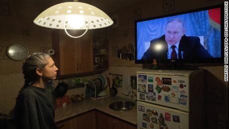 A woman watches Putin speaking during a TV broadcast of a meeting of the National Security Council on the recognition of the self-proclaimed Donetsk People&#39;s Republic and the Luhansk People&#39;s Republic on February 21, 2022. 