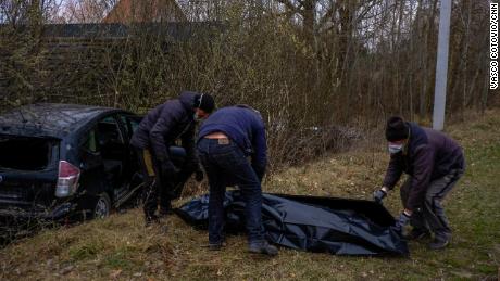 Volunteers collect the body of a man who was shot while driving his car in Borodianka, Ukraine.
