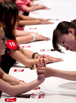 A judge checks on the contestants' nails during a nail art creative design contest at the China 2011 Hair and Beauty exhibition in Beijing, China.