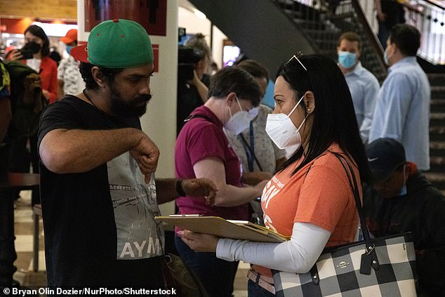 A charity worker from Catholic Charities speaks to one of the migrants who arrived from Texas