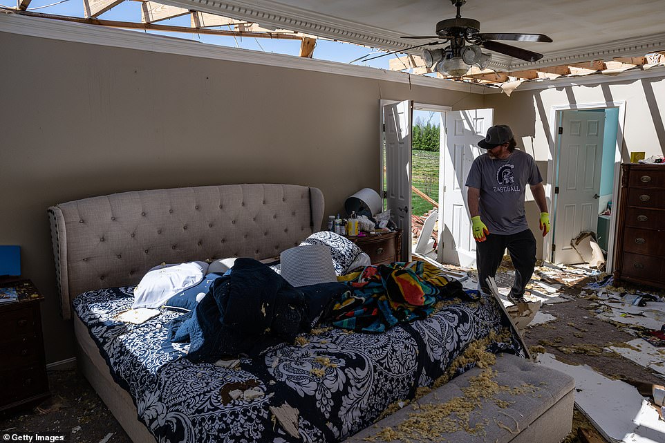 Jim Gross searches through a bedroom for recoverable items in a heavily damaged home in the Glenmary subdivision on April 14, 2022 in Louisville