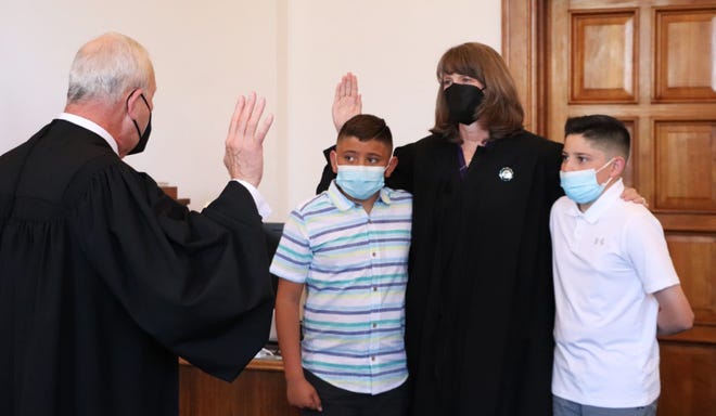 Justice C. Shannon Bacon of the New Mexico Supreme Court, takes the oath of office as chief justice on April 13, 2022, alongside her nephews Tristan and R.J. Bacon.