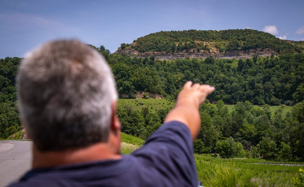 Tracy Neece gestures to the high walls left behind on his property after a strip mining operation failed to reclaim the site in Floyd County, Kentucky. July 15, 2021