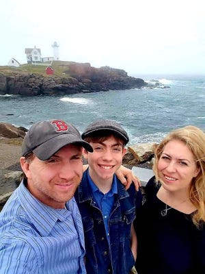 From the left, Jody, Owen and Erica Clark are seen in front of the Nubble Lighthouse in Cape Neddick in the town of York, Maine.