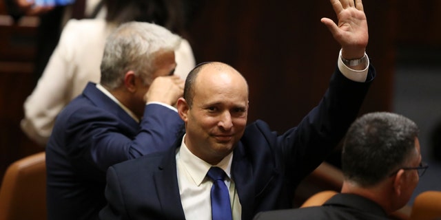 Israel's new prime minister Naftali Bennett raises his hand during a Knesset session in Jerusalem Sunday, June 13, 2021.