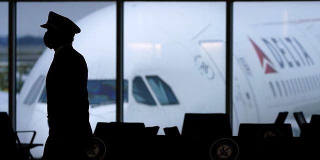 FILE: A Delta Airlines pilot wears a face mask as he walks through a terminal at Hartsfield-Jackson International Airport in Atlanta, on Thursday, Feb. 18, 2021. 